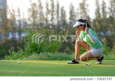 Sporty asian woman golf player crouching  50685787