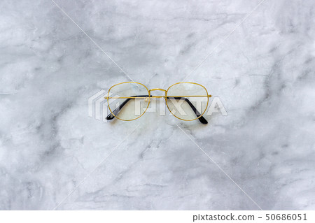 Stylish gold eyeglasses spectacles on marble background. Top view Copy space Minimal style Stylish gold eyeglasses spectacles on marble background. Top view Copy space Minimal style 50686051