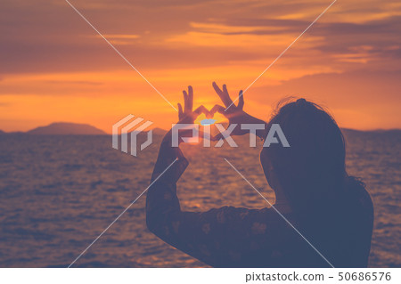 Silhouette woman hand is making a heart-shaped 50686576