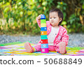 An outdoor picture of the baby try to make a tower 50688849