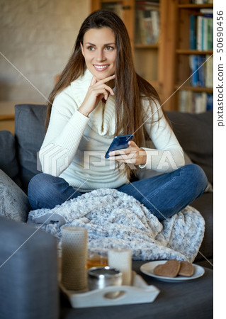 woman in white sweater texting on her phone 50690456