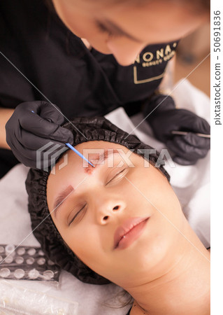 Top view of beauty specialist applying treatment for tattoo removal on her patient 50691836