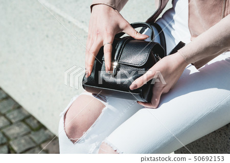 Women's hands open a Black Leather bag 50692153