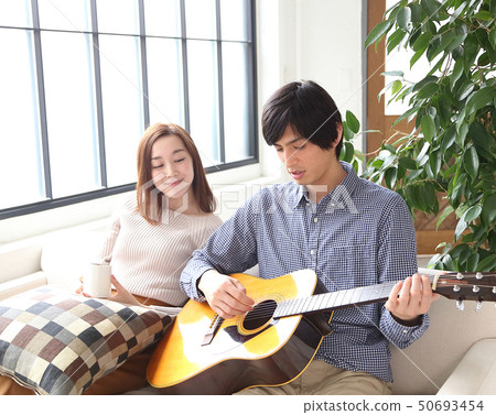 Image of a boyfriend and her girlfriend playing the guitar 50693454