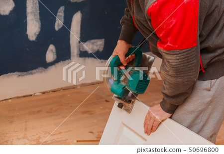 man using a circular saw for cutting wood door 50696800