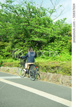 Female college student riding a bicycle 50697604