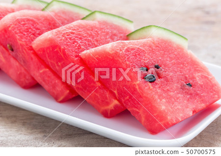 Watermelon is cut into pieces in a white dish. Watermelon is cut into pieces in a white dish. 50700575