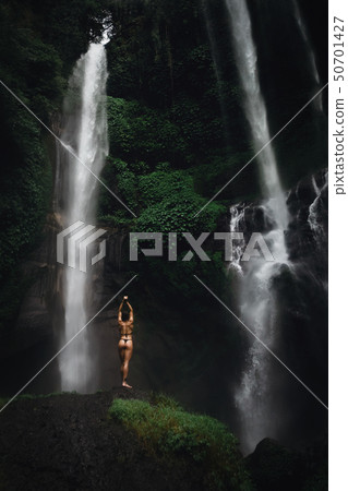 Beautiful young woman in bikini relaxing in front of waterfall. Ecotourism concept image travel girl 50701427