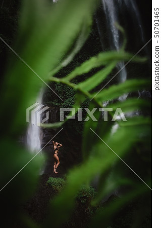 Beautiful young woman in bikini relaxing in front of waterfall. Ecotourism concept image travel girl 50701465