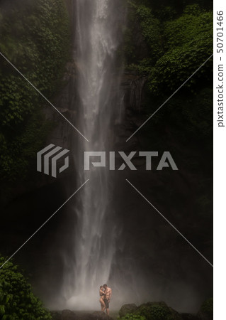 Young couple enjoying the freshness of nature under a waterfall in the tropics. The young pair 50701466