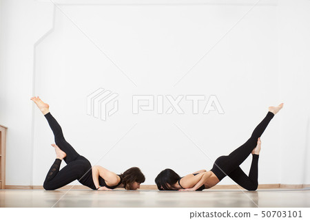 Two sporty girl on white background doing acroyoga, yoga with