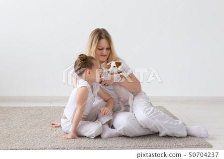 people, family and pets concept - mother and daughter sitting on the floor with puppy Jack Russell 50704237