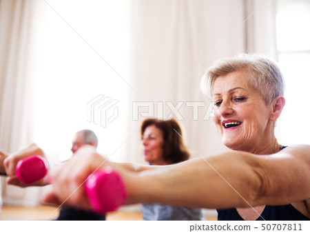 Group of senior people doing exercise with dumbbells in community center club. Group of senior people doing exercise with dumbbells in community center club. 50707811