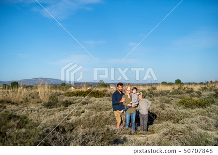 Young family with two small children standing outdoors in nature. Young family with two small children standing outdoors in nature. 50707848