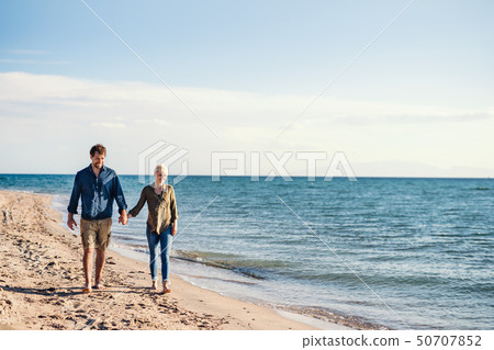 Young couple walking outdoors on beach, holding hands. Copy space. Young couple walking outdoors on beach, holding hands. Copy space. 50707852