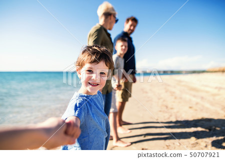 Young family with two small children standing outdoors on beach. Young family with two small children standing outdoors on beach. 50707921
