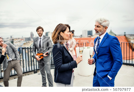 A group of joyful businesspeople having a party outdoors on roof terrace in city. 50707977