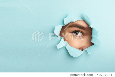 Nude Makeup. Female Eye With Mascara Looking Through Torn Blue Paper Nude Makeup. Female Eye With Mascara Looking Through Torn Blue Paper 50707984