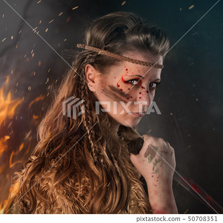 Beautiful young Amazon female warrior posing in a fighting stance with a dagger. Beautiful young Amazon female warrior posing in a fighting stance with a dagger. 50708351