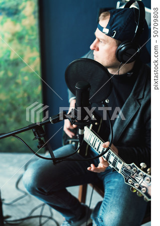 Close up of a man singer sitting on a stool in a Close up of a man singer sitting on a stool in a 50709808