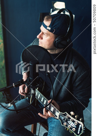 Close up of a man singer sitting on a stool in a Close up of a man singer sitting on a stool in a 50709809