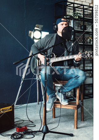 Close up of a man singer sitting on a stool in a Close up of a man singer sitting on a stool in a 50709812