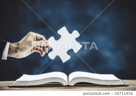 Person with chunky book and puzzle pieces Person with chunky book and puzzle pieces 50711458