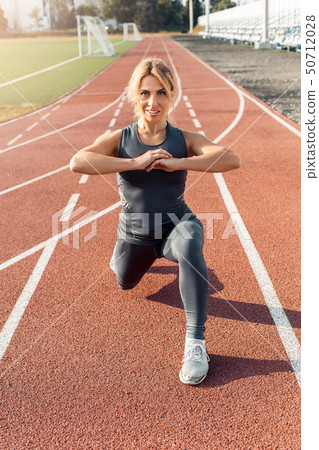 Sporty Lifestyle. Young woman on stadium step forward stretching leg on track smiling motivated Sporty Lifestyle. Young woman on stadium step forward stretching leg on track smiling motivated 50712028