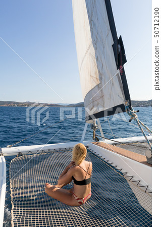 Beautiful woman relaxing on a summer sailing cruise, sitting and sunbathing in hammock of luxury 50712190