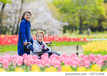 Woman caring for elderly woman in wheelchair Woman caring for elderly woman in wheelchair 50712480