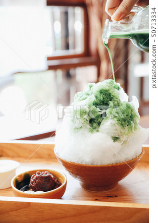 Delicious Japanese sweet shaved ice green tea on wooden table in japanese cafe Delicious Japanese sweet shaved ice green tea on wooden table in japanese cafe 50713334