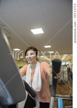 體育健身房圖像騎交叉訓練機的女人 體育健身房圖像騎交叉訓練機的女人 50713713