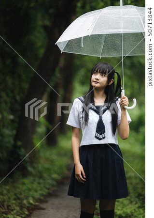 Portrait of Asian school girl walking with umbrella at nature walkway on raining Portrait of Asian school girl walking with umbrella at nature walkway on raining 50713844