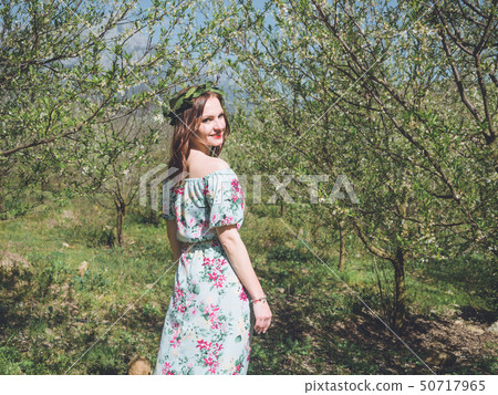 Young beautiful woman in spring blossom trees. 50717965