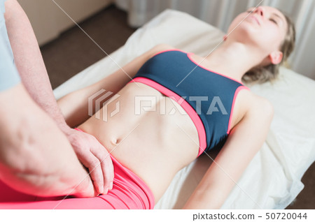 Male manual visceral therapist masseur treats a young female patient. External editing of the uterus Male manual visceral therapist masseur treats a young female patient. External editing of the uterus 50720044