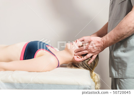 Male manual visceral therapist masseur treats a young female patient. Head and ear massage Male manual visceral therapist masseur treats a young female patient. Head and ear massage 50720045