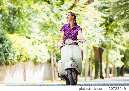 Young woman riding old scooter Young woman riding old scooter 50722949