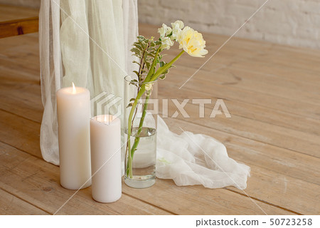 Branch of blooming white peony tulip Mattiola branch in a glass vase white wax candles stand on the Branch of blooming white peony tulip Mattiola branch in a glass vase white wax candles stand on the 50723258