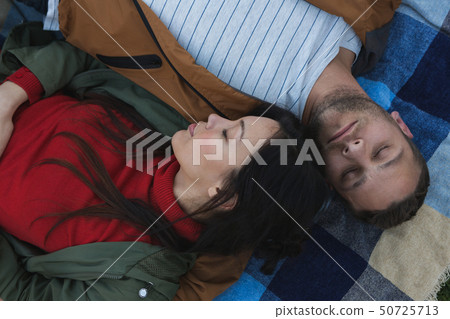 Couple sleeping on picnic blanket in the park 50725713