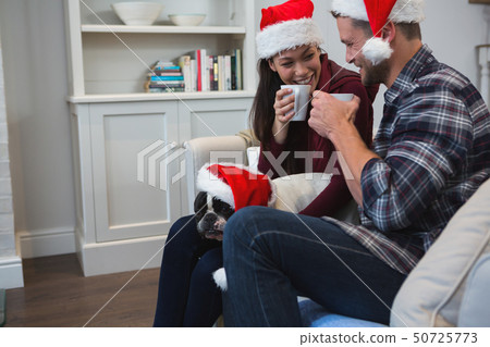 Couple having coffee with their pet dog in living room 50725773
