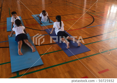 Schoolkids doing yoga on a yoga mat in school 50725932