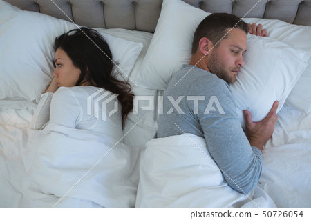 Angry couple avoiding each other in bedroom Angry couple avoiding each other in bedroom 50726054