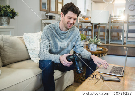 Man using digital camera in living room Man using digital camera in living room 50726258
