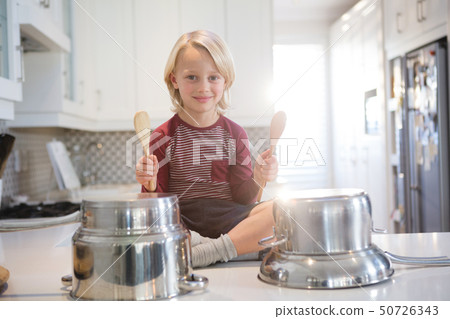 Boy playing with utensils in kitchen Boy playing with utensils in kitchen 50726343