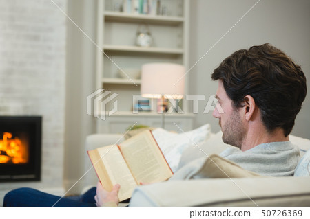 Man reading a book in living room 50726369