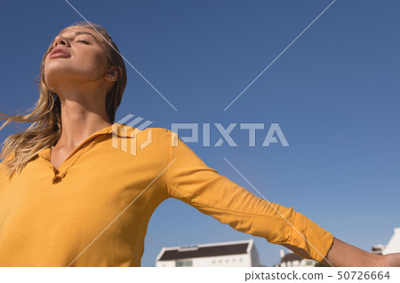 Woman standing with arms outstretched on the beach Woman standing with arms outstretched on the beach 50726664