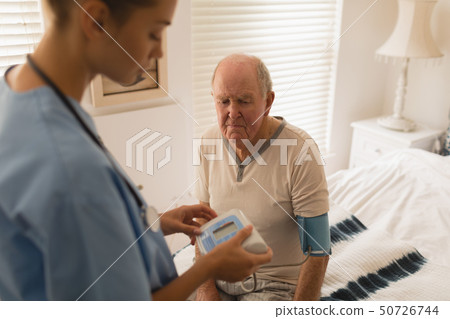 Female doctor checking blood pressure of senior man Female doctor checking blood pressure of senior man 50726744