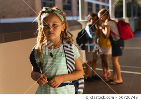School friends bullying a sad girl in hallway of elementary school School friends bullying a sad girl in hallway of elementary school 50726749