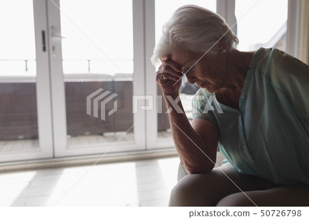 Worried senior woman sitting in living room Worried senior woman sitting in living room 50726798