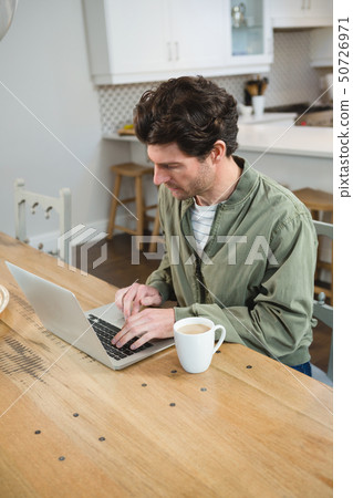 Man using laptop in kitchen 50726971